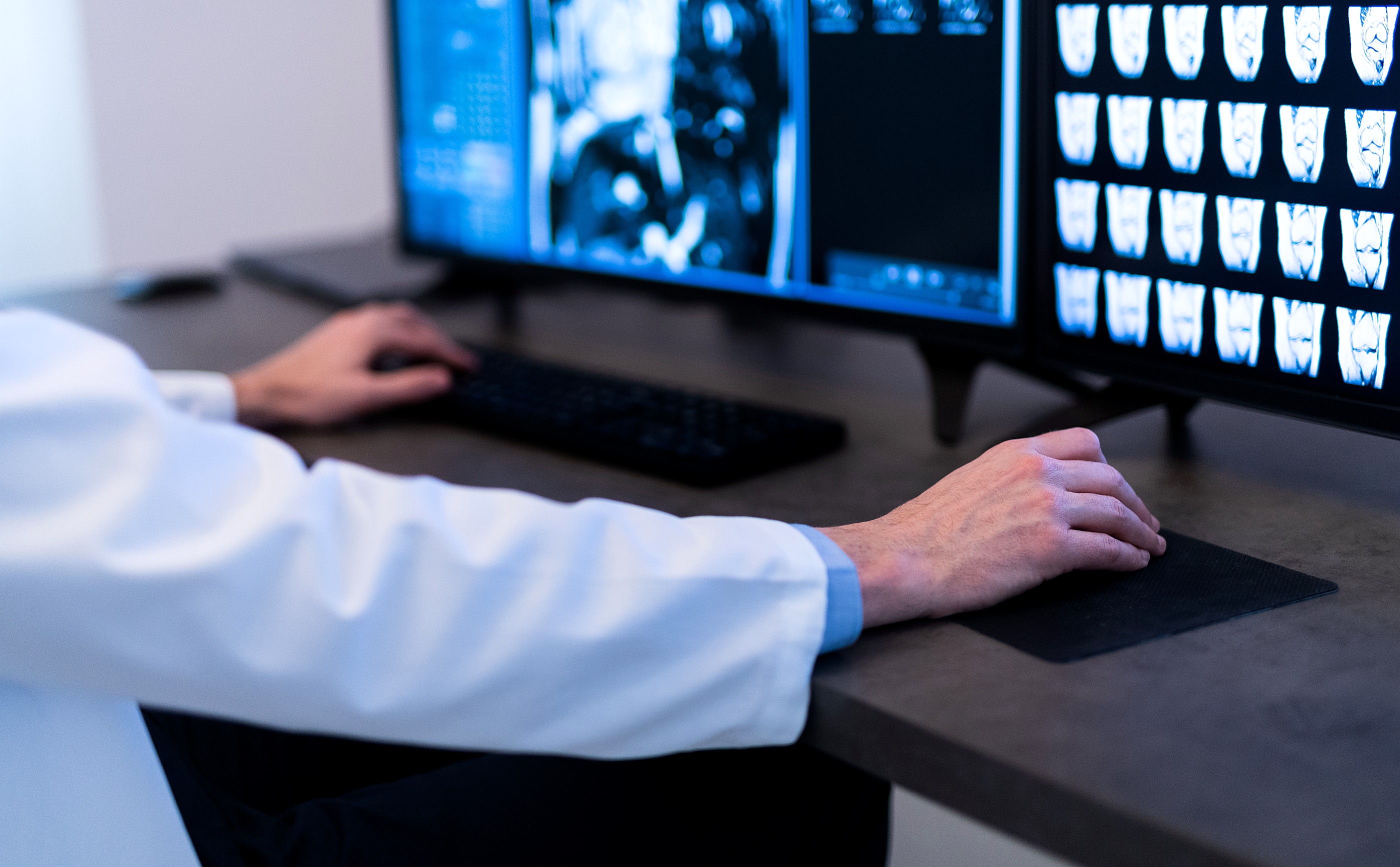 A radiologist reviewing MRI and CT scan images at a workstation